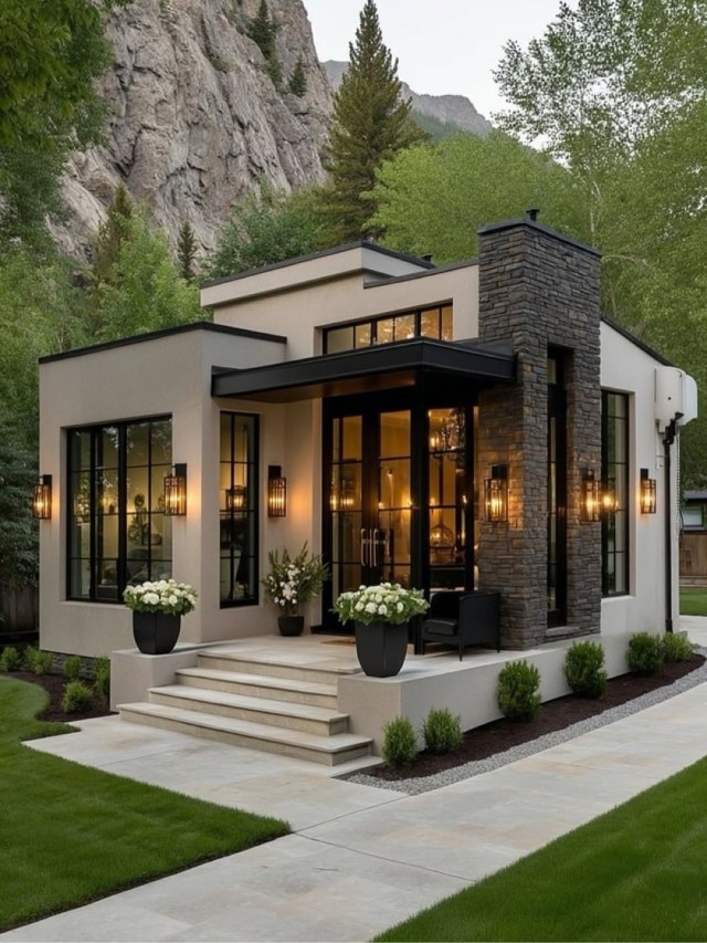 Modern small house with stucco walls, stacked-stone column, black-framed windows and glowing lantern-lit entry porch