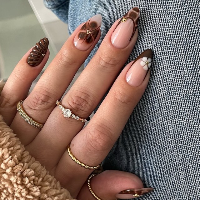 Almond nails with nude bases, brown French tips, sculpted 3D flowers and tiny gold bead accents